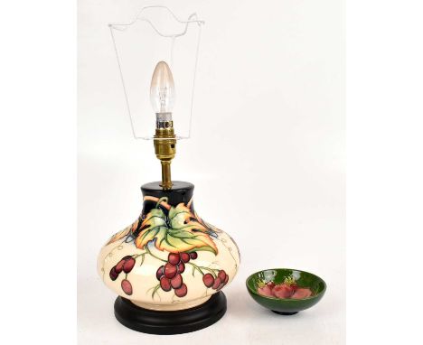 MOORCROFT; a lamp decorated with fruit and foliate design, together with an 'Anemone' pattern pin dish, height of lamp 20cm.