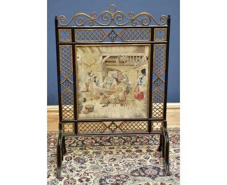 A black painted and gilt bentwood fire screen with central tapestry depicting the interior of an inn, height 112cm.