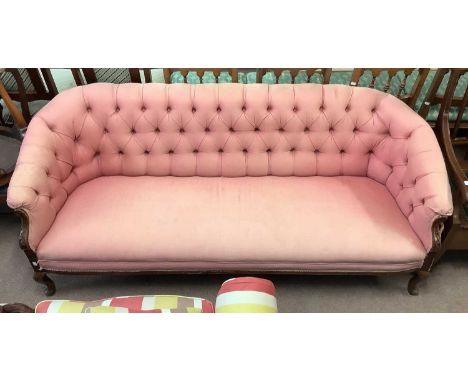 A late 19th century button back sofa, upholstered in a salmon pink material, on carved cabriole supports.