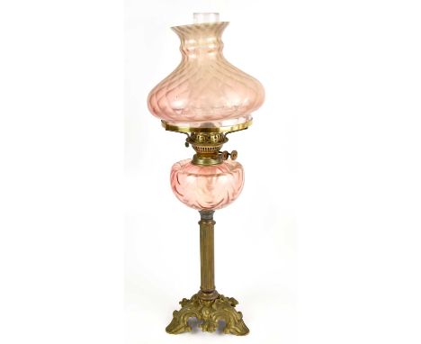 An early 20th century brass oil lamp with pink shade, height 66cm.