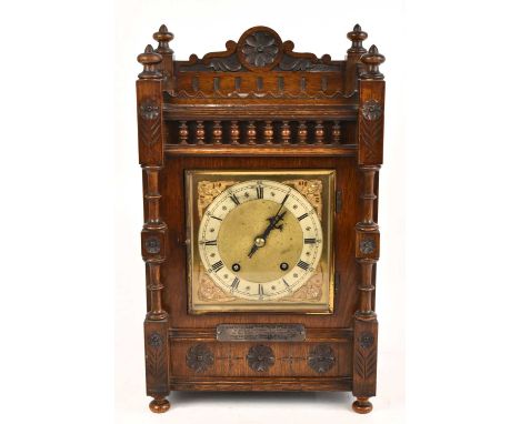 A large late 19th century oak cased mantel clock, the dial set with Roman numerals, with a white metal plaque with presentati