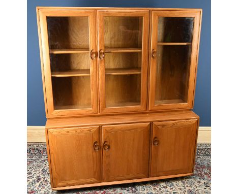 ERCOL; a light elm dresser, the back section with three glazed doors above three panelled cupboard doors, terminating on cast