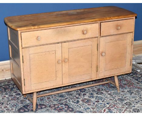 ERCOL; a mid century light elm sideboard with two drawers above three panelled cupboard doors on turned column supports, widt