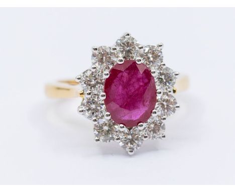 A ruby and diamond 18ct gold cluster ring, comprising a central oval mixed cut ruby approx 2.25carats, within a border of rou