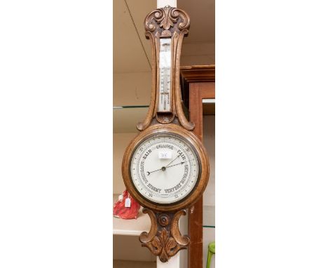 A mid 20th Century banjo barometer cased in oak with carved detail