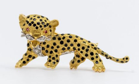 A Cartier style ruby and diamond set gold metal brooch in the form of a leopard, ruby set eyes, black enamel markings and dia