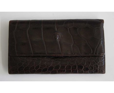 A Versace crocodile skin wallet, with button clasp, numerous interior pouches and card compartments, single zipped compartmen
