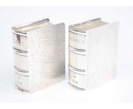 A pair of unusual contemporary silver salt and pepper shakers, each in the form of a book with opposing engine turned exterio