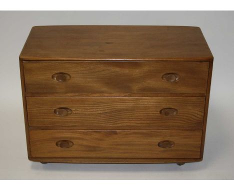 A 1960s Ercol blond elm low chest of three long drawers, raised on roller castors, h.65.5cm, w.91cm, d.48cm