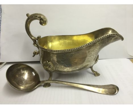 A George III silver sauceboat London 1771, maker's mark II. Plain oval form with bead border, leaf capped flying scroll handl