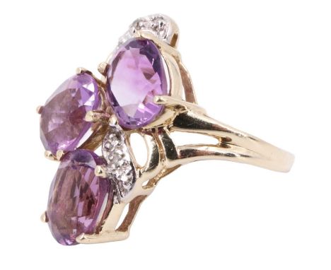 A late 20th Century amethyst dress ring, having three 8 x 6 mm ovals randomly set over an entwining white metal ribbon set wi