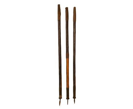Three South African hardwood spear shafts, each decorated with bands of woven wire and carrying a small spearhead at one end