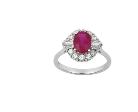 An 18 Carat White Gold Ruby and Diamond Cluster Ringthe oval cut ruby within a border of round brilliant cut diamonds, with b