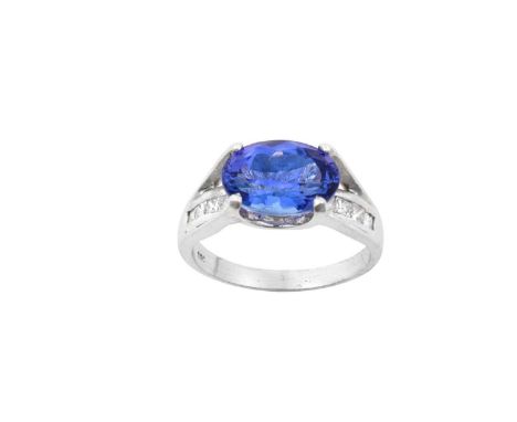A Tanzanite and Diamond Ringthe oval cut tanzanite in a white four claw setting, set above a row of princess cut diamonds in 