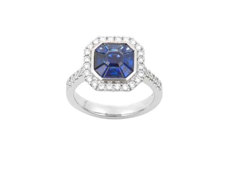 An 18 Carat White Gold Sapphire and Diamond Ring, by Hirsh Londonan emerald-cut sapphire within a border of vari-sized trapez