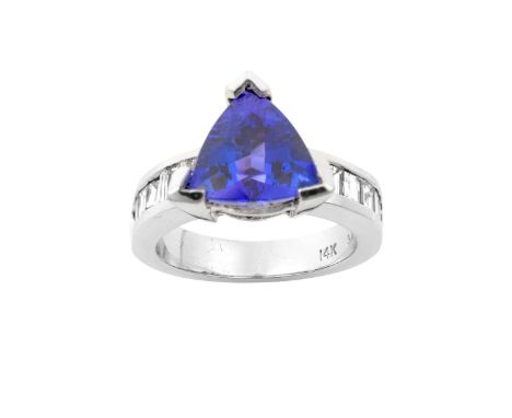 A Tanzanite and Diamond Ringthe trilliant cut tanzanite in a white claw setting, to baguette cut and tapered baguette cut dia