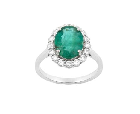 An Emerald and Diamond Cluster Ringthe oval cut emerald within a border of round brilliant cut diamonds, in white claw settin
