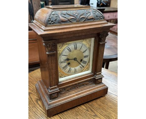 An Art Nouveau inspired mantle clock with a carved top, the dial with Roman numerals on a plinth base 