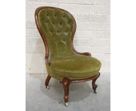 A Victorian walnut-framed spoon-back low salon chair with buttoned back, on cabriole front legs with ceramic castors. 