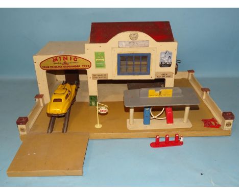 A Minic garage with advertising signs and two-vehicle lifts, pumps, etc, a Minic car base 42 x 60cm and a scratch-built fort,