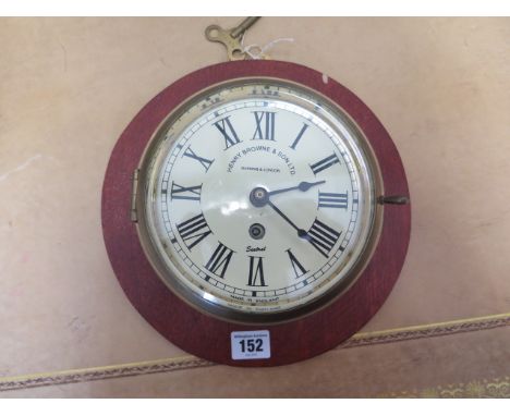 A brass bulkhead clock Sestral by Henry Browne on a wooden mount, working with key, clock 18cm diameter, mount 26cm diameter 