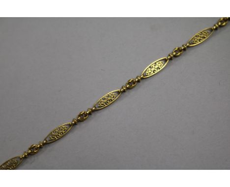 A yellow metal filigree bracelet, composed of pierced long oval links with chain-link spacers (tests as 24ct), 7.7g