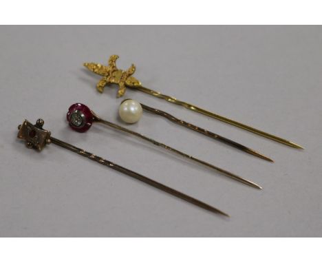 A Victorian ruby and diamond stick pin and three other stick pins, one with fleur-de-lys terminal marked 14K, one with pearl 