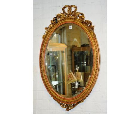 A Victorian giltwood oval wall mirror, with ornate foliate bow decoration, 91cm high x 55cm wide