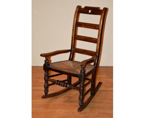 An 18th century style ladder back rocking armchair, with woven rush seat, 102cm high