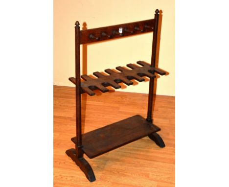 An oak stick stand/shoe rack, with six pegs to either side of top, above a further six recesses to either side of middle, 96c