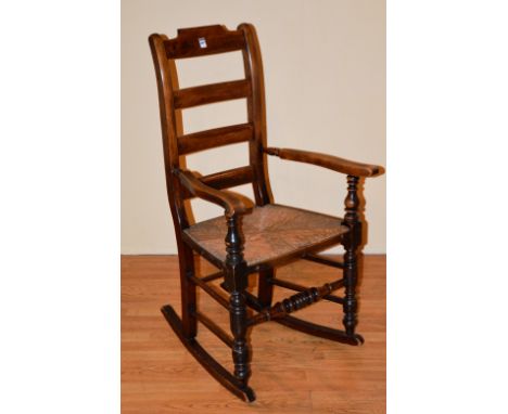 An 18th century style ladder back rocking armchair, with woven rush seat, 112cm high