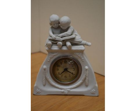 A 20th century Bisque porcelain figural mantel clock, depicting two young children reading a book to top and moulded swags to
