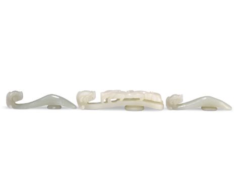 THREE CHINESE CARVED JADE BELT HOOKS,&nbsp;each with dragon-head terminals, one with a carved dragon shaft. (3) 8cm, 8.5cm an