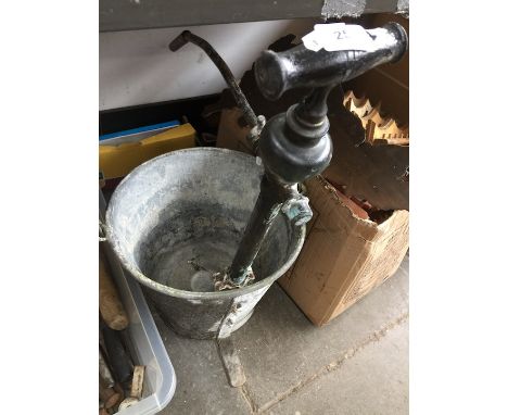 A vintage water pump attached to a galvanized bucket  