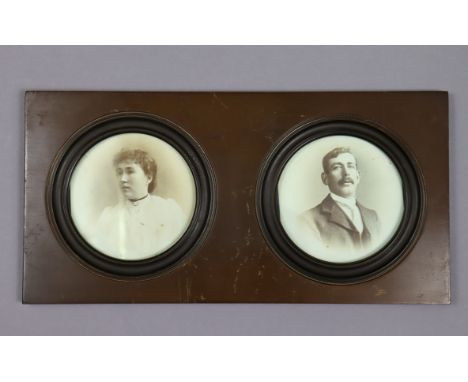 A pair of Edwardian male &amp; female photograph portrait studies (circular), 4” diam., displayed in one glazed frame, 6¾” x 