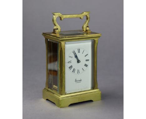 Another brass-cased carriage clock with black roman numerals to the white enamel dial, signed “Harrods London”, 5” high.
