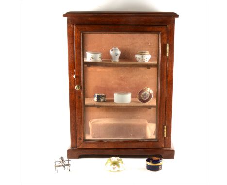 Collection of miniatures, including Royal Worcester pieces, in a display cabinet