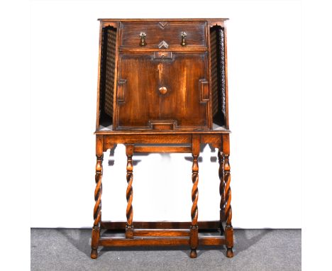An oak escritoire, fitted with a single drawer over a flap front, enclosing a fitted interior, caned panelled sides, barleytw