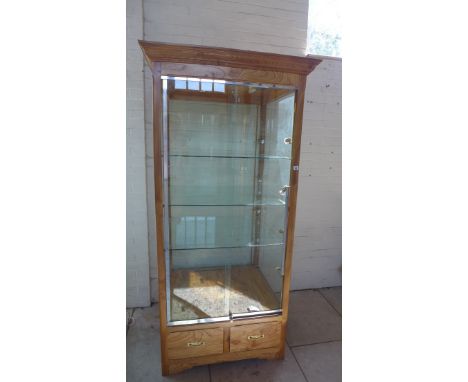 A good quality wooden shop display cabinet with 2 sliding lockable doors, lighting, 3 adjustable shelves and 2 base storage d