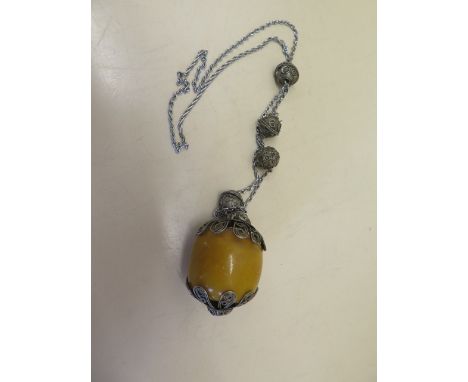 An Asian white metal and amber style necklace, the m large amber or resin bead measures 5x4.5cm, total weight 110 grams 