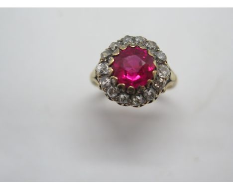 An 18ct synthetic ruby and diamond cluster ring, the central stone (Red synthetic corundum )having a diameter of approx 8mm, 