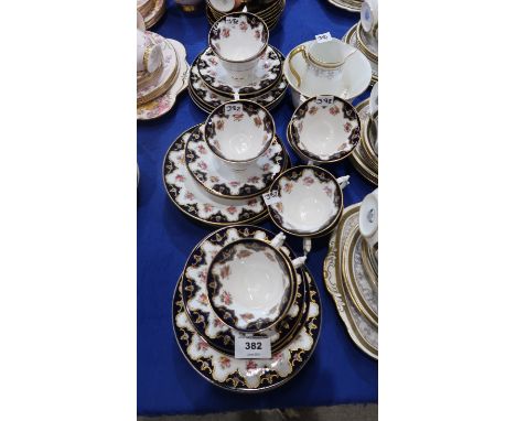 A Royal Worcester teaset decorated with a band of roses below a dark blue and gilt border, comprising eleven cups, seven sauc