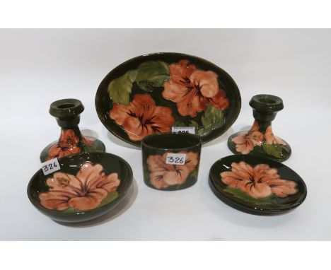 A collection of Moorcroft Hibiscus pattern pieces including a pair of dwarf candlesticks, an oval dish, a small bowl, a trink