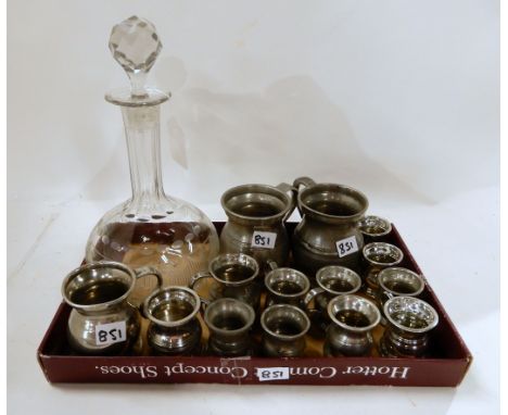 A lot comprising a glass decanter and fourteen assorted pewter measures Condition Report: Available upon request