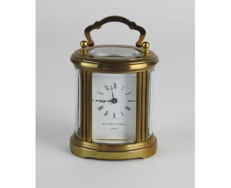 A 20th century oval carriage timepiece, the 1.25 inch white enamel dial signed 'Mathew Norman, London' under a ring of Roman 