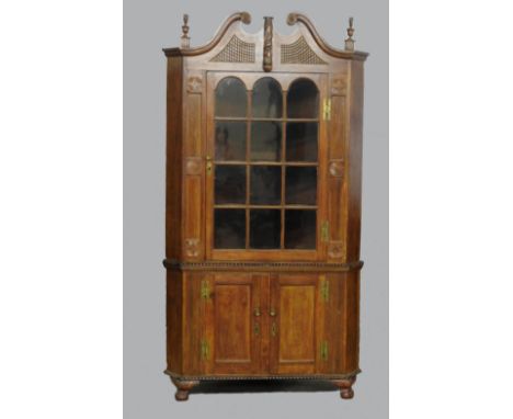 A 19th century American cherrywood full height floor standing corner cabinet in the Chippendale style, the double scroll pedi