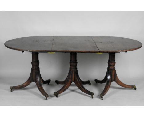 A 20th century mahogany Regency style three pillar dining table, with rounded ends and multi line moulded edge on three short