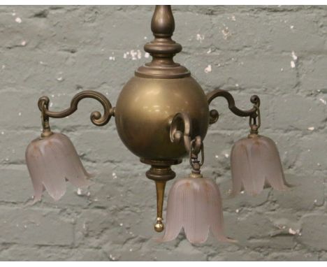 A brass three branch hanging lamp with frosted glass shades.