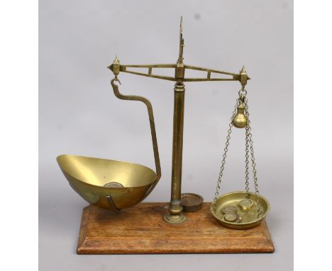 A pair of Victorian brass balance scale mounted on a oak plinth along with a selection of weights.