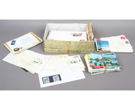 A box of colour British and foreign postcards along with British stamps and first day cover.